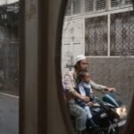 Man and child on motorcycle reflected in an oval frame